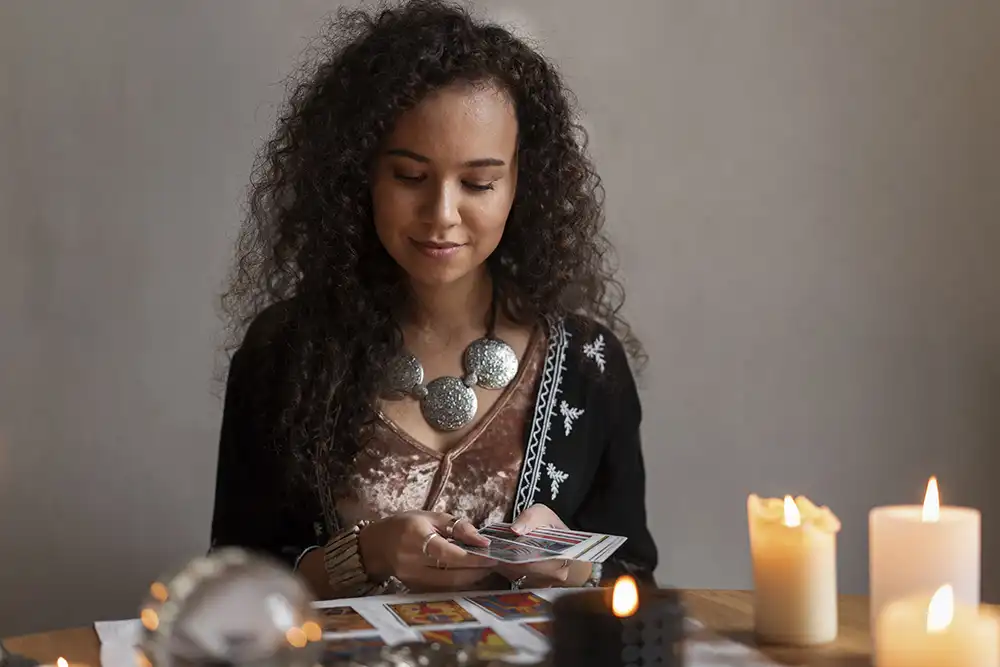Vidente escolhendo cartas de tarô junto a velas